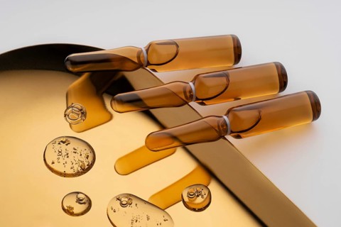 Elegant golden ampoules filled with anti-aging serum, strategically placed on a reflective surface