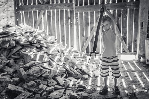 Little boy working in a shed with pitchfork