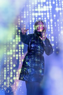 An elderly Asian woman interacts with the vibrant digital realm of the metaverse, showcasing