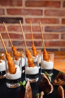 Close-up of crispy skewered appetizers artfully served in shot glasses filled with a creamy dipping
