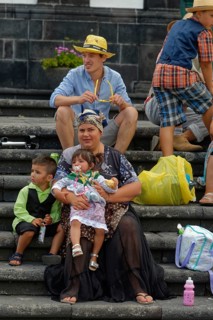 Mother in traditional dress holding two children on a staircase, Fenais da Luz, Sao Miguel Island,