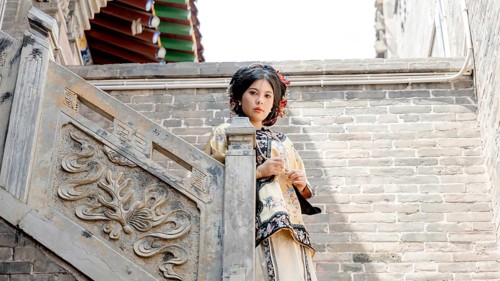 A woman dressed in traditional Qing dynasty clothing stands on an ornate stone staircase in