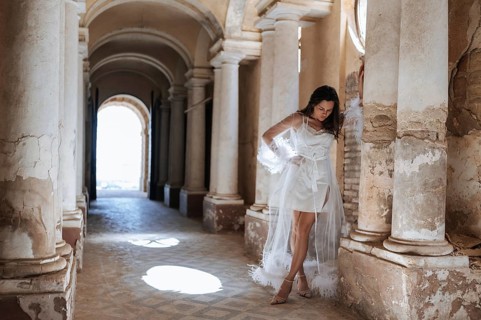 A bride poses elegantly in a flowing white gown amidst the historic architecture of an ancient