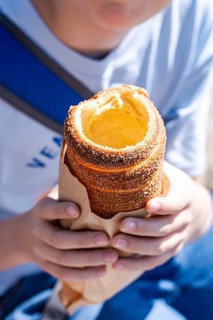 Young boy enjoying a traditional Czech trdelnik pastry outdoors, showcasing its crispy