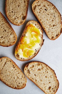 Top view of freshly sliced homemade sourdough bread topped with butter and jam, served on a