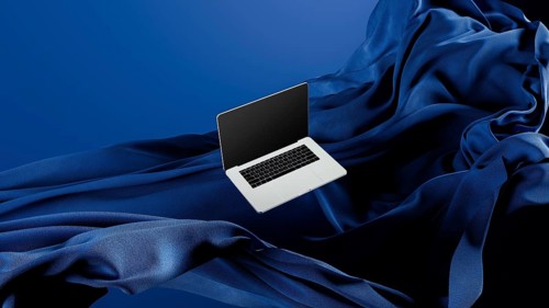 A sleek laptop is placed atop smooth fabric, showcasing its lightweight design against a rich blue
