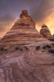 Majestic sandstone formations tower under a radiant sunset sky in Coyote Buttes, located in the