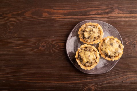 Tartlets with meat and cheese on brown wooden background. top view, flat lay, copy space