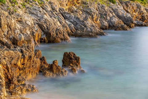 Crystal clear and turquoise water on the beach of Ustrine Bay on a sunny day at sunset on the