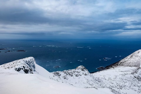 View of open sea from snow-capped peaks, Senja Island, Troms, Norway
