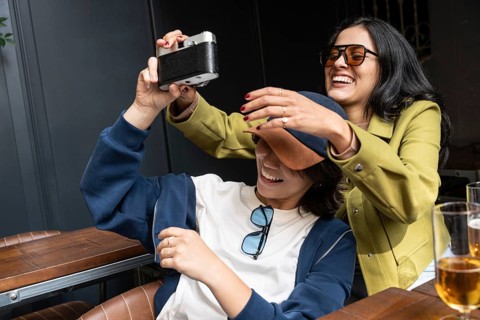 A joyful couple captures a happy moment together with a camera. They are laughing, expressing