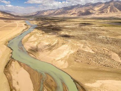 Aerial view of a winding river cutting through the barren yet stunning landscape of Ladakh, nestled