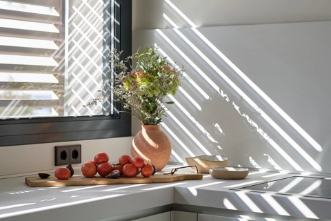 A stylish kitchen displays a natural light setting, enhancing a clay vase with fresh flowers and a