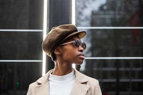 Stylish black woman in sunglasses and a brown hat, radiating urban elegance Captures modern,