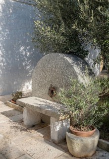 Small stone bench in front of an old millstone, Apulia, Italy