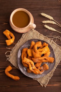 Crunchy biscuit Brushwood cookies sprinkled with powdered sugar on brown wooden background and