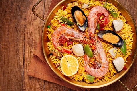 Seafood paella, in a frying pan, on a wooden table, no people