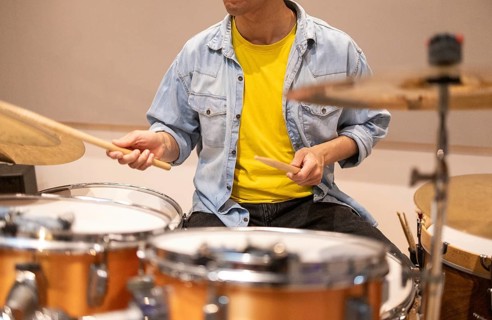 A musician energetically plays the drums in a professional recording studio. The scene captures