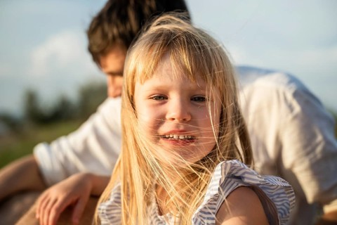 A joyful little girl smiles brightly on a warm summer day in Italy. Her blonde hair flows in the
