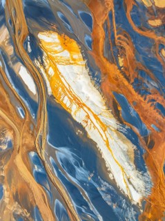 Top view of an abstract aerial nature scene showing intertwining textures of earth and water in