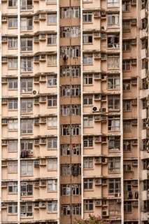 The image captures the facade of a high-rise residential building in Hong Kong. Numerous air