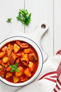 Potatoes stewed with meat, in tomato sauce, with spices and herbs, no people, on a white table