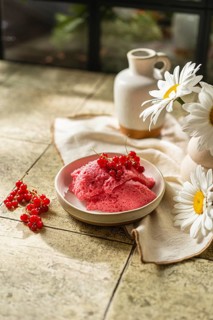 From above freshly made pink berry mousse garnished with red currants, placed in a ceramic bowl