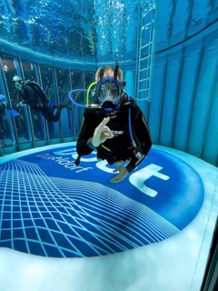 Scuba diver in diving tower of Messe boot Düsseldorf makes international diving sign hand signal