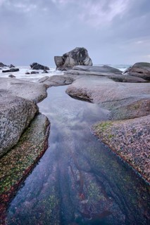 Rocks on beach of fjord of Norwegian sea in winteron sunset. Utakliev beach, Lofoten islands,