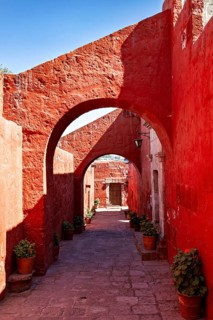 A shady corridor with strong red arches and tasteful flower pots, The Santa Catalina Monastery in