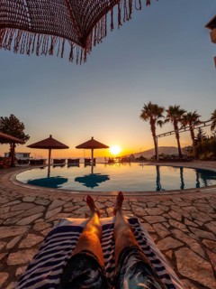 Feet of a man in a pool enjoying a sunset on summer vacation