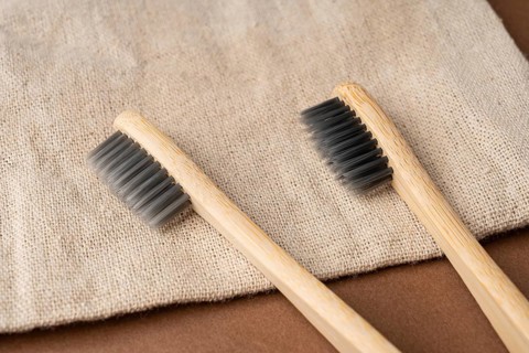 From above view of two eco-friendly bamboo toothbrushes with charcoal bristles resting on a