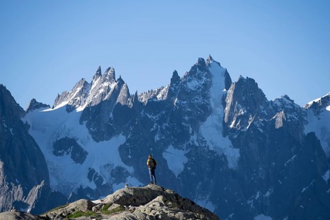 Young man in front of impressive mountain landscape in morning light, pointed rocky icy mountain