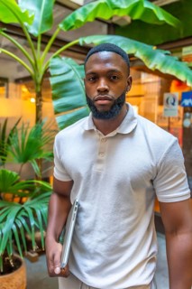 Vertical portrait of a casual and serious african man holding laptop outside a coworking office
