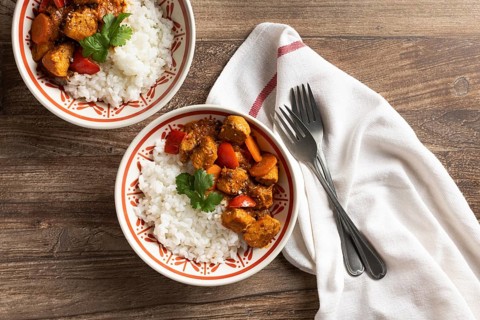 Top view of two bowls of Hungarian pork goulash served with white rice, garnished with fresh