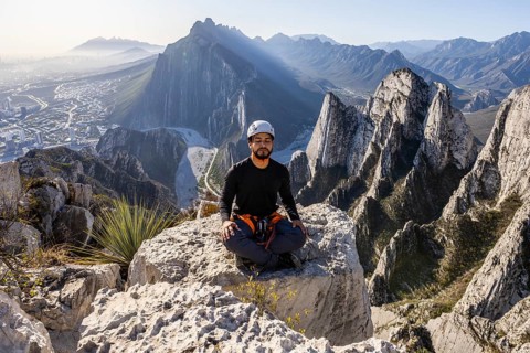 A man in mountaineering gear sits calmly on a rocky edge at Eagleâ€™s Nest, Monterrey, Mexico,