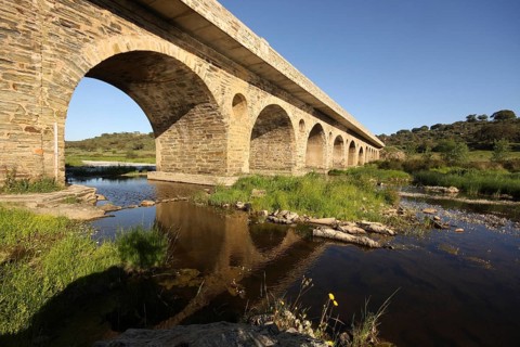 Stone arch bridge with reflection, across the Rio Almonte south of Torrejon El Rubio, landscape,
