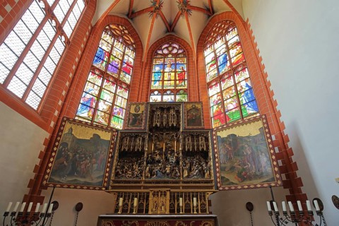 High altar with colorful church windows, candles, paintings, stained glass, handicrafts, choir