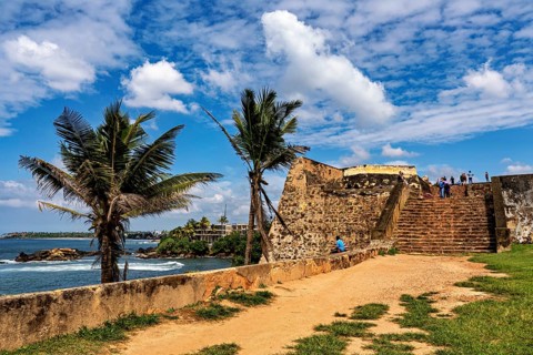 A historic fortress with palm trees under blue skies on the ocean, The fortress of Galle in Sri