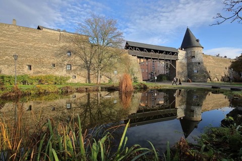 Historic city fortification with Helmswartsturm and wooden bridge and reflection in the pond,