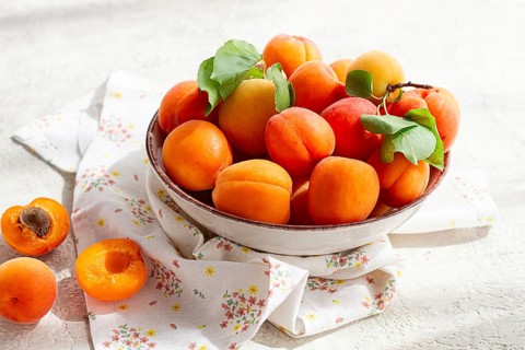 Fresh apricots in a bowl, on a bright table, natural light, top view, no people