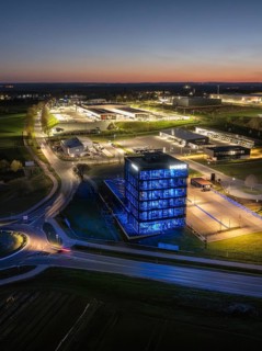 A modern illuminated building surrounded by streets and other structures at night, Nagold, Black