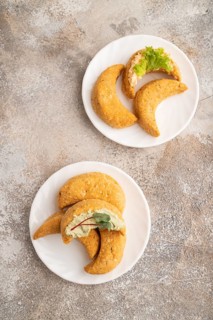 Homemade salted crescent-shaped cheese cookies on brown concrete background. top view, flat lay,