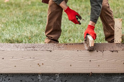 Construction Worker Leveling Wet Cement Into Wood Framing