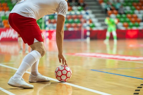 Detail of futsal ball and player out of the court