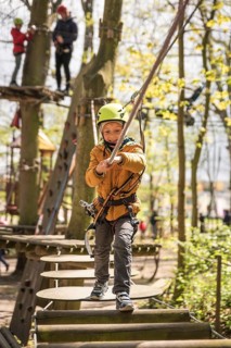 Portrait of cute little boy walk on a rope bridge in an adventure rope park