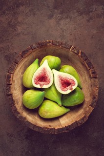 Fresh green figs, in a wooden plate, top view, close-up, no people