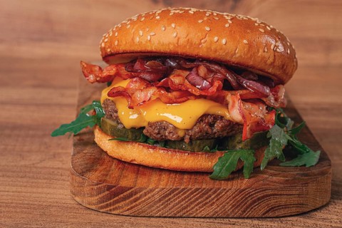 Burger with beef and bacon, with arugula and caramelized onions, pickles, sauce, homemade, no
