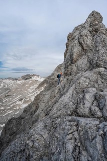 Mountaineer with helmet climbing on the rock, on a narrow rocky ridge, crossing the Jubiläumsgrat,