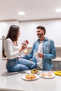 Young couple sharing a conversation over coffee and breakfast pastries in their contemporary
